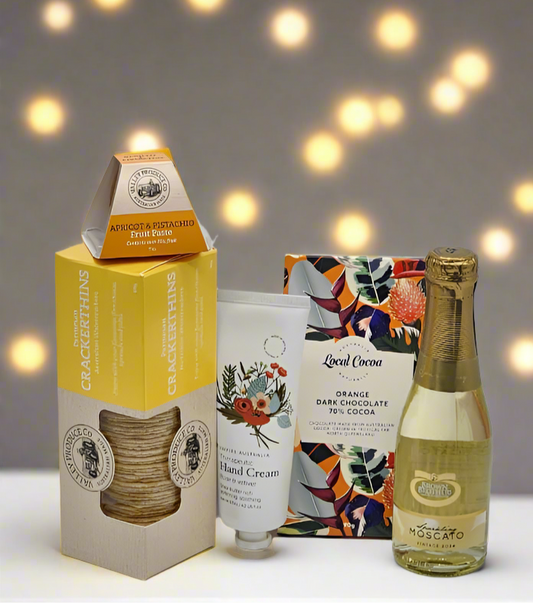 Collection of products including a bottle, cream, and boxes on a light background with blurred lights.