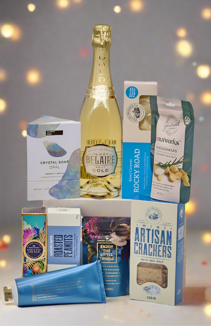 Assorted gourmet food and drink items including a bottle of champagne and packaged snacks on a blurred background.
