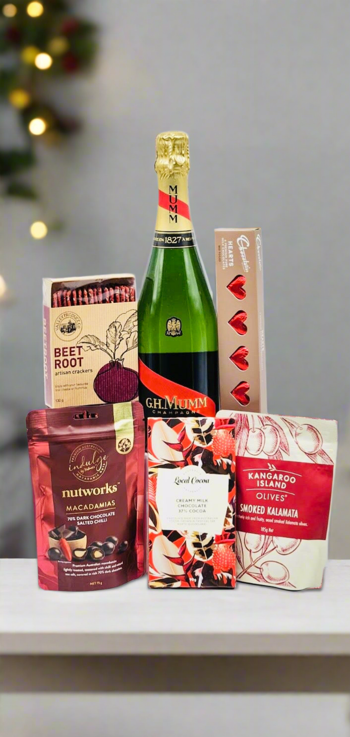 Bottle of champagne with assorted snacks on a surface, blurred lights in the background